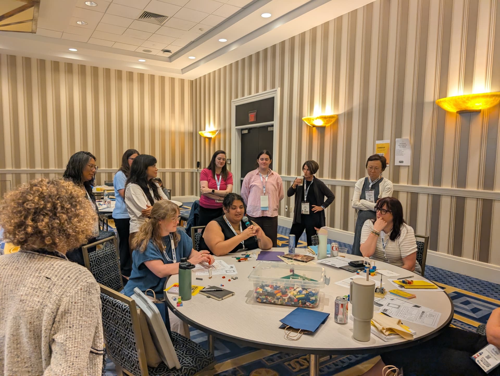 A full room gathers around one table to hear a build get explained.