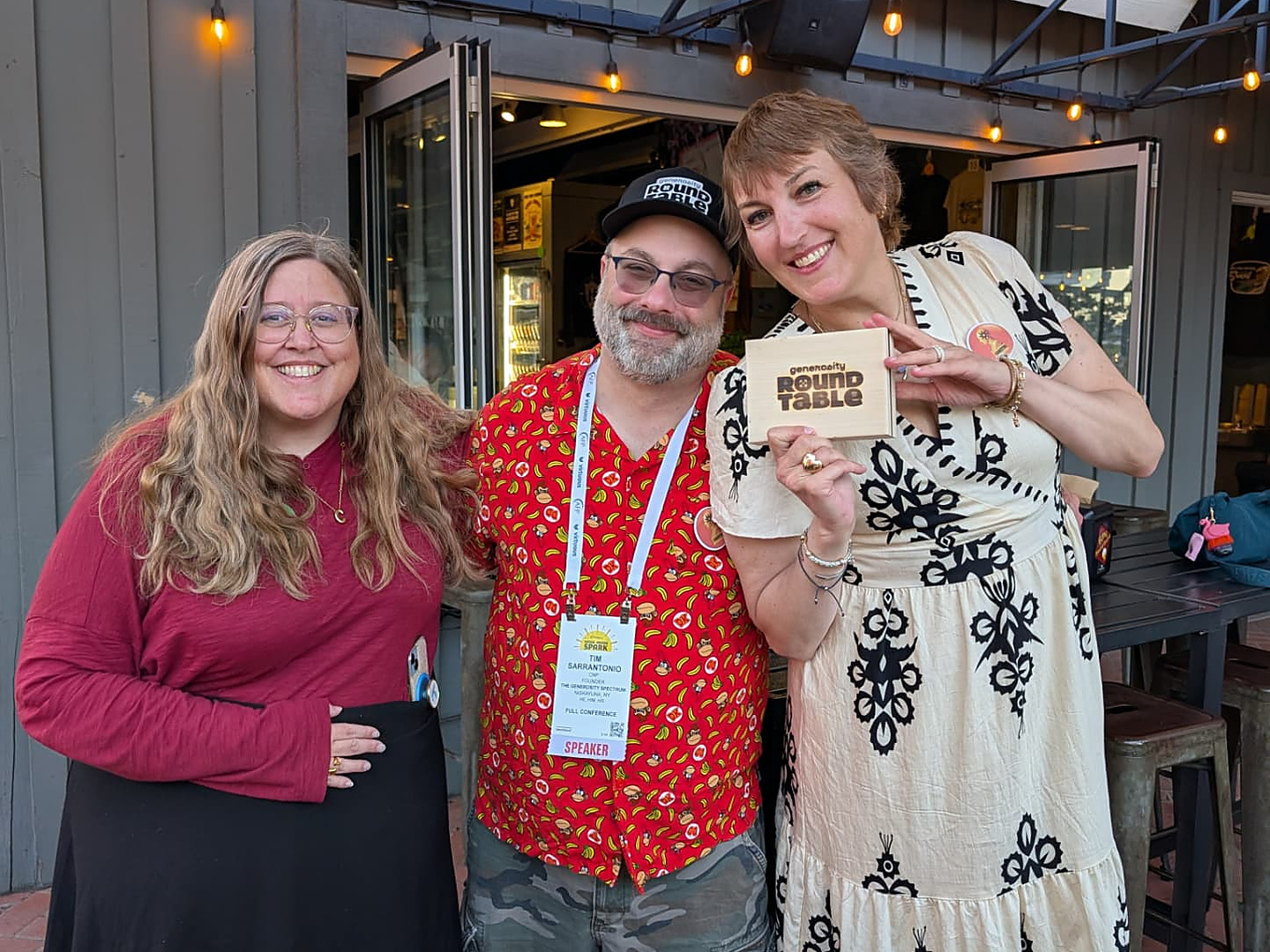Tim Sarrantonio with two partners holding a Generosity Roundtable box at a conference