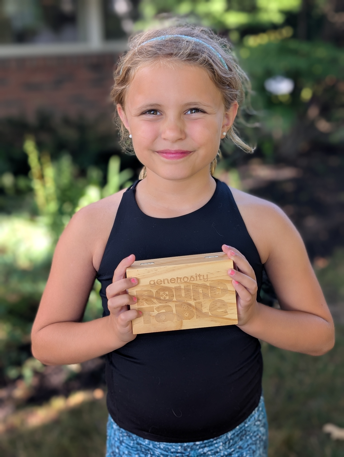 Maggie, Tim's daughter, holding a miniature Generosity Roundtable box